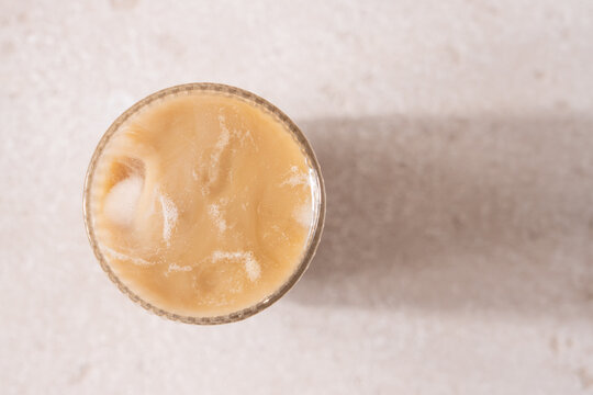 Macro Top View of Iced Caramel Cappuccino  in Clear Glass on Beige Background, Minimalist Coffee Aesthetic, Copy Space, Refreshing Cold Drink Concept