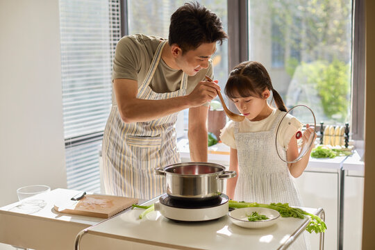 A stay-at-home dad and his daughter cooking in the kitchen