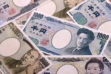 Japanese yen money bills pile on table. Japan banknotes of JPY currency close up. © Larysa