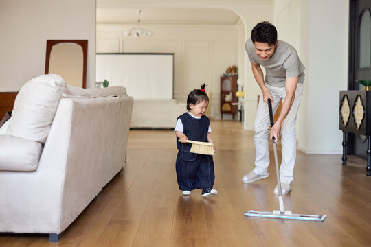 A stay-at-home dad cleaning the house with his baby girl as his little helper