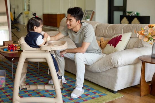 A stay-at-home dad feeding his baby formula