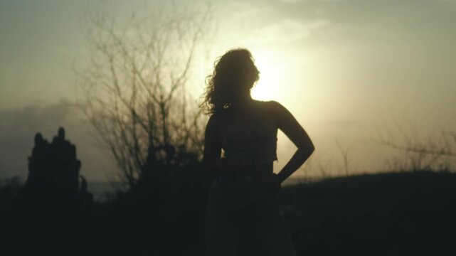Woman silhouette at a golden sunset, partially covering the sun on the coastal horizon, backlit scene in warm evening light, concept of empowerment, awareness, personal freedom, inner strength.