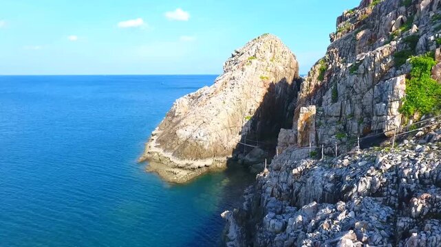 Aerial drone view of rugged rocky coastline with steep cliffs meeting clear blue ocean water creating dramatic coastal landscape on Ly Son Island in central Vietnam