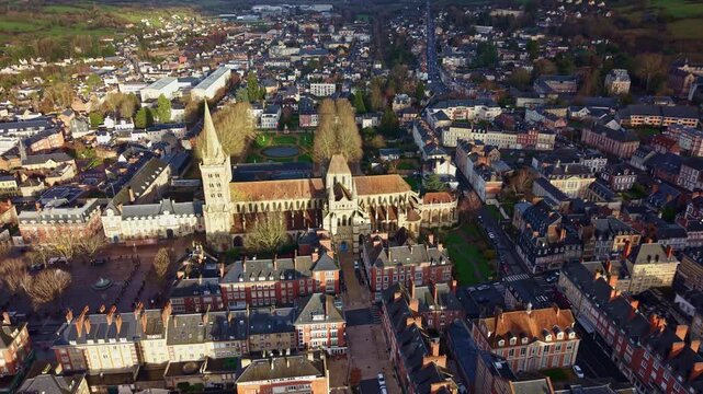 Drone flying toward Saint Peter Cathedral revealing illuminated gothic architecture and surrounding townscape of Lisieux in Normandy France.