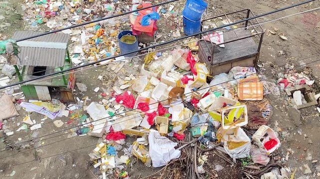 Dog searching food into plastic and paper waste on polluted slum area. Environmental damage.