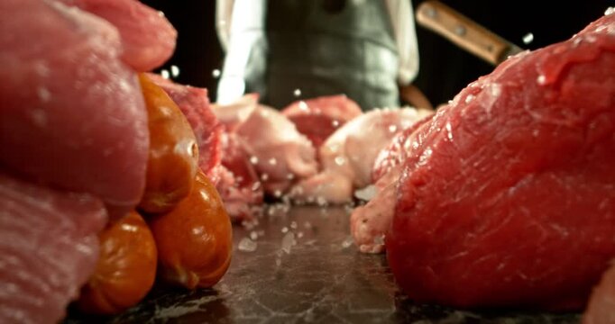Super Slow Motion of Chef Throwing Salt and Spice on Raw Meat. Filmed on High Speed Cinema Camera.  Meat Preparation Concept, Fire on Background. Camera Placed on Motion Control System.