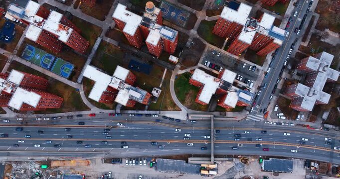 Moving over the highways wit hectic traffic. Drone footage over the tops of high reddish-brown apartment complexes in the neighborhood of New York, USA.