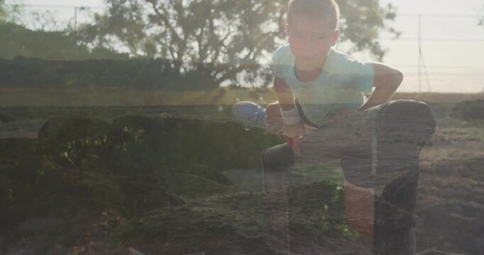 Boy placing hands on wooden rail shifting weight, swinging leg over to cross in outdoor education