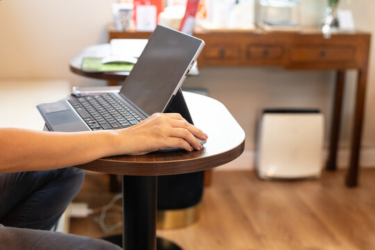 Woman working on tablet on wooden table in a cozy cafe.