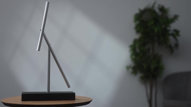 Minimalist magnetic pendulum on a wooden table in a modern interior. Kinetic desk sculpture with soft light, copy space and blurred background for balance and motion concepts.