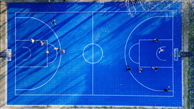 Aerial view of a vibrant blue basketball court speckled with shadows and players engaged in a game, Belgrade, City of Belgrade, Serbia.