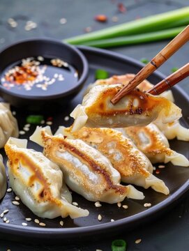Savoring gedza with cabbage and pork served on a plate at a dining table with dipping sauce and garnish