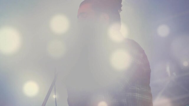 Male singer holding mic causing lens flare and singing music while lights and haze revealing shadow