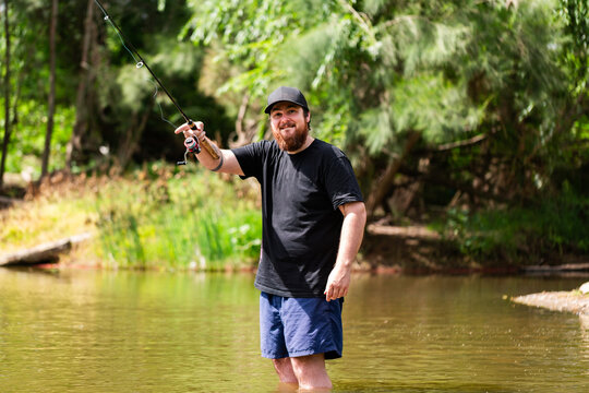 Happy person fly fishing in river standing in the water in summertime