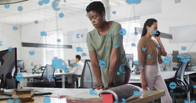Blue icons appearing and growing, woman leaning over desk marking plans aligning design in office
