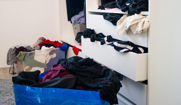 Messy closet wardrobe full with unfolded and hanging female cloths 