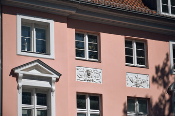 Fototapeta premium Architectural Heritage In Stralsund Germany A Pink Building With Ornate Windows And Decorative Reliefs Showcasing European Cityscapes And Historical Preservation