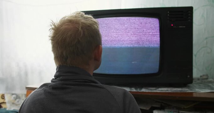Man staring at CRT television with Analog TV static display. Television hypnosis and attention capture concept