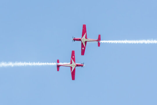 Aerial view of two red and white aircraft performing a synchronized aerial display, with trails of white smoke, Changi Exhibition Centre, Singapore Air Show 2026, Singapore.