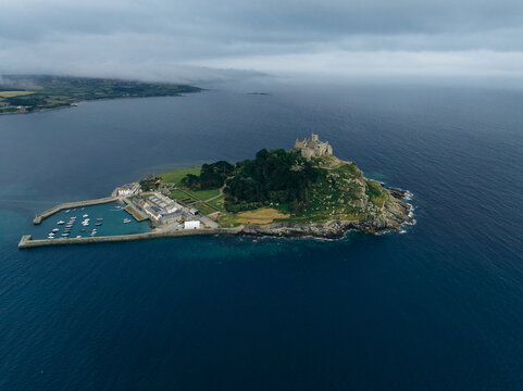 Aerial view of St Michael's Mount rising majestically from the dark blue sea, its ancient stone walls crowned with a castle, Marazion, England, United Kingdom.