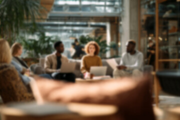 Fototapeta premium Blurred Diverse team collaborating in modern office lounge