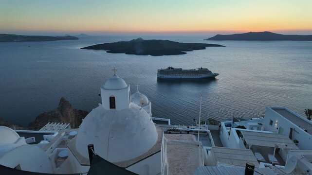 A cruise ship sails past Santorini, Greece, at sunset, offering stunning views of the caldera and Aegean Sea from the iconic white-domed churches.