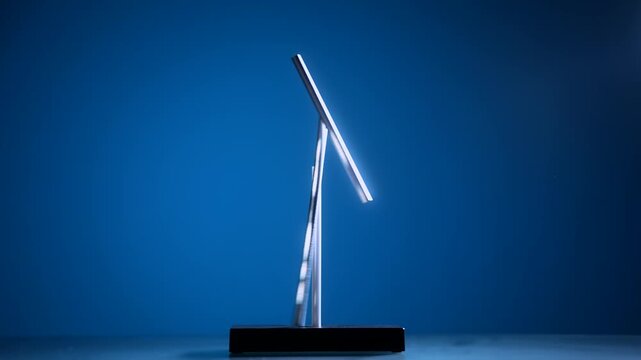 Minimalist magnetic pendulum desk sculpture balancing on blue background. Modern kinetic object for balance, motion, physics and design concepts.