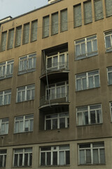 Fototapeta premium Concrete apartment block with stacked balconies, repetitive windows, weathered concrete, small metal railings, utilitarian