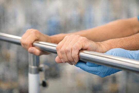 Patient Practicing Hand Strength Exercise Using Parallel Bars in Rehabilitation