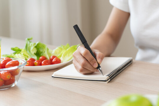 Wellbeing of health with good food control concept. Woman writing the meal note and plan to eat during diet program to loss weight goal for balance nutrition and calories.