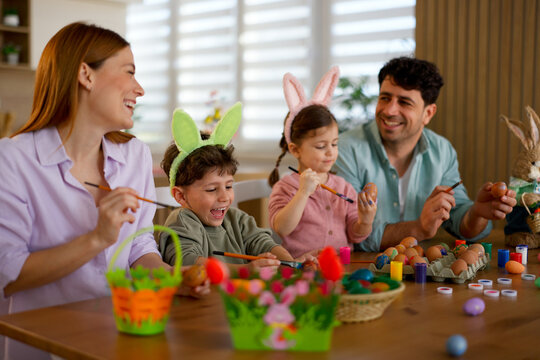 Joyful caucasian family celebrating easter while painting eggs