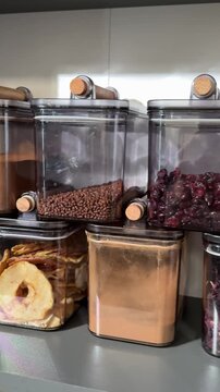Variety of grains red green yellow dal rice sesame methi legumes in glass jars displayed on a dark black slate surface copy text space frame 