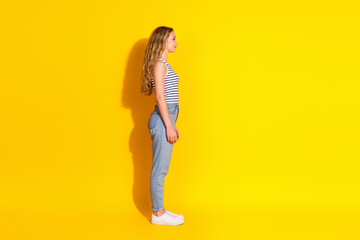 Young woman in casual outfit standing against a vibrant yellow background exuding confidence and...