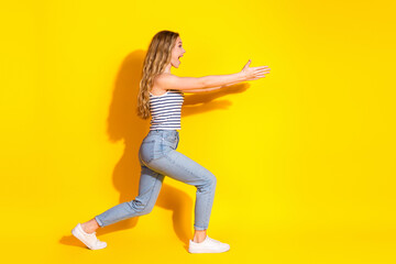 Young joyful woman in casual outfit posing cheerfully against vibrant yellow background under...
