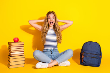 Cheerful young student with book and backpack on bright yellow background appreciating student life
