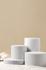 Natural cosmetic background for product presentation. White podiums on the sand. Front view.