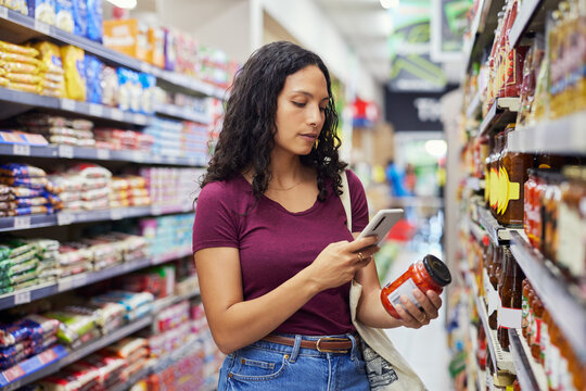 Young woman scanning jar of cherry tomatoes for ingredients