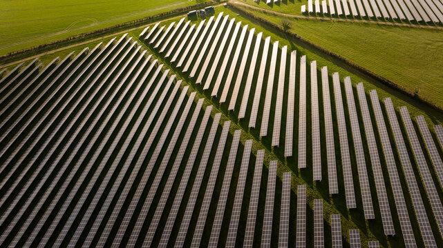 Aerial view of rows of solar panels casting long shadows over the green fields, Blandford Forum, Dorset, United Kingdom.