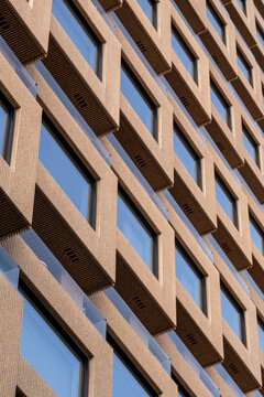 Modern concrete building facade with windows and geometry pattern showing textured architecture detail creating a clean modern background for design