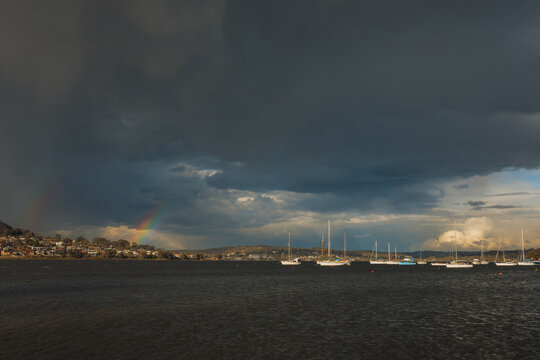 Rainbow appears over Lake Macquarie with sailboats under stormy skies