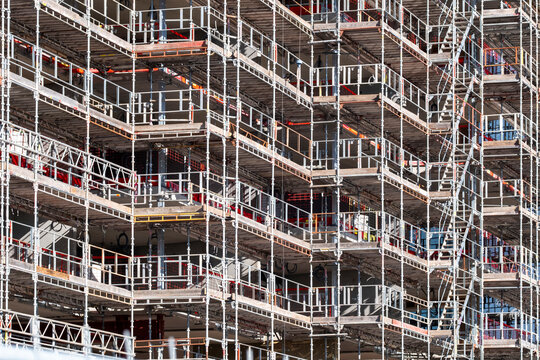 Urban construction scaffolding framework with metal platforms and structural grid pattern for building renovation work