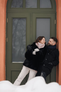 Happy couple in love embracing near building in city during walk in winter 
