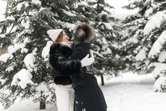 Side view of romantic couple hugging in snowy winter park  