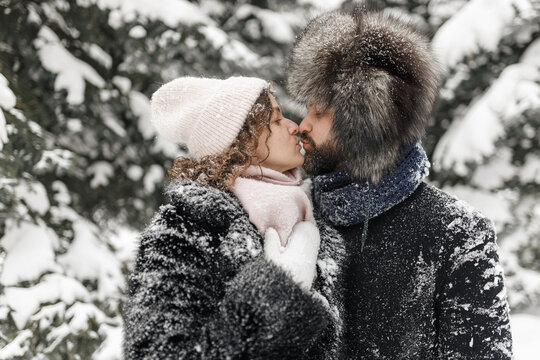 Side view of couple in love kissing in snowy winter park 