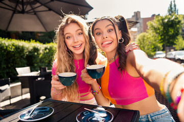 Funny sunny cafe moment two best friends travel city together sharing laughter and stylish vibes during a bright summer day