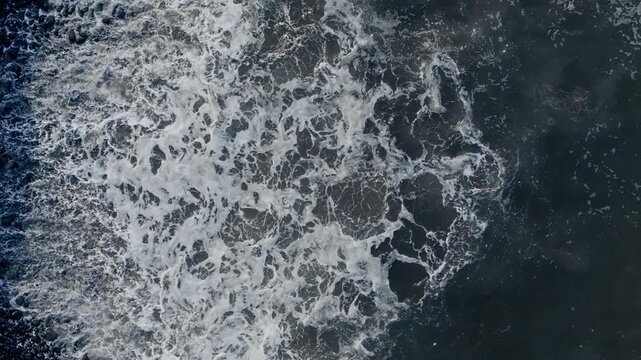 Atlantic Ocean wave front rolling across pebble shoreline, continuous movement of water and foam lines