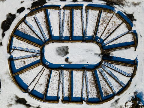 Aerial view of a striking oval structure with blue accents and snow-covered segments, contrasting against the surrounding winter landscape, Arnes, Skeida- og Gnupverjahreppur, Iceland.