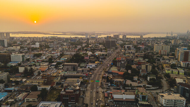 Aerial view of a sprawling cityscape bathed in the golden hues of the setting sun, creating a mesmerizing contrast between the shadows and illuminated buildings, Lagos, Lagos, Nigeria.