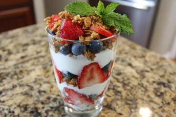 Yogurt parfait layering fresh fruit, granola, and mint