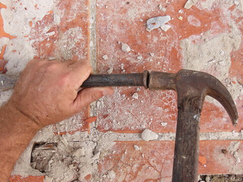 Closeup of man hands holding hammer and steel chisel for breaking up the floor. Working on renovation concept.